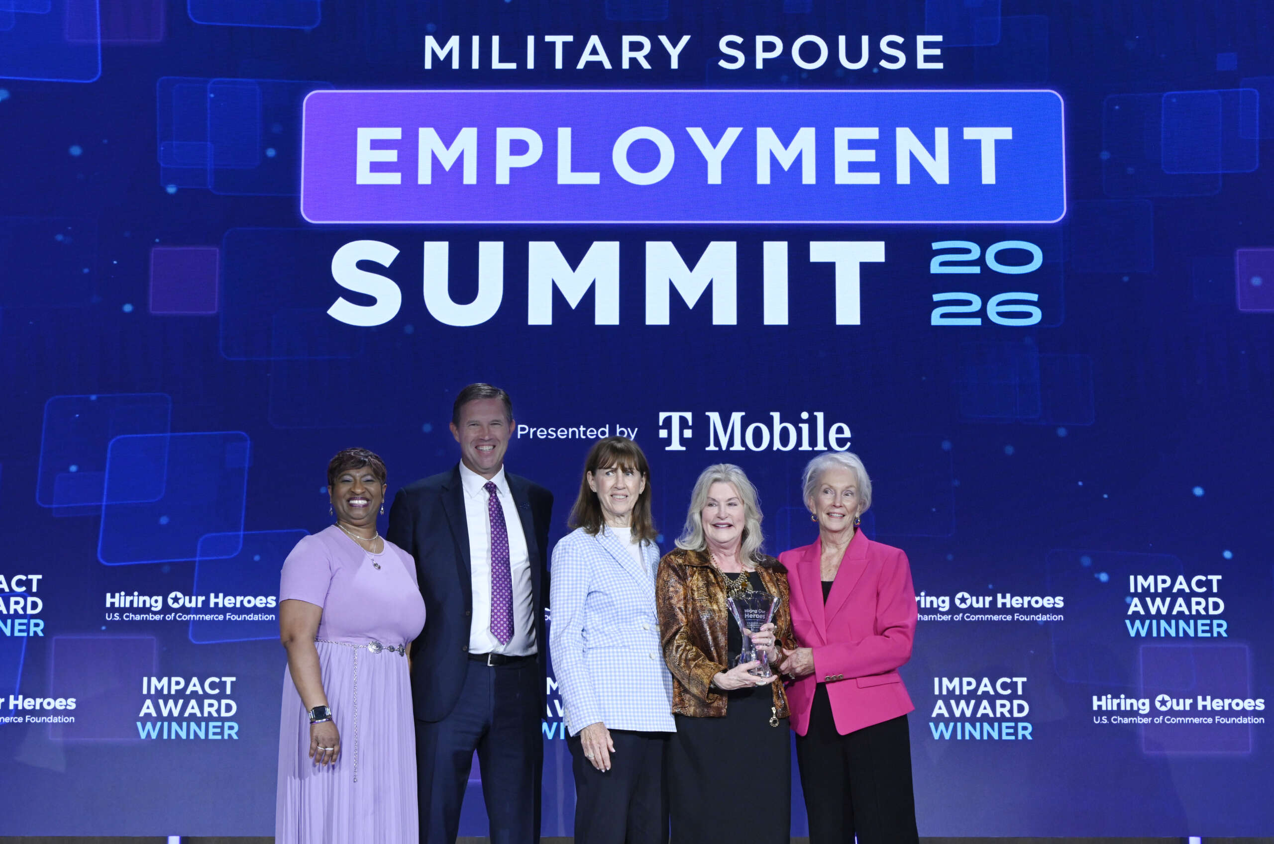 Five individuals pose on stage at the Military Spouse Employment Summit 2026, presented by T-Mobile, with one holding an Impact Award.